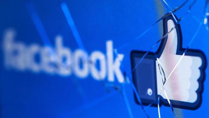 der logo von dem sozialen netzwerk facebook, ein gebrochener bildschirm eines laptops, eine kleine weiße hand