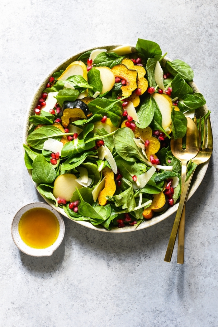 kohlenhydratfreis essen, gesunder salat mit spinat und granatapfelsamen, goldenes geschirr
