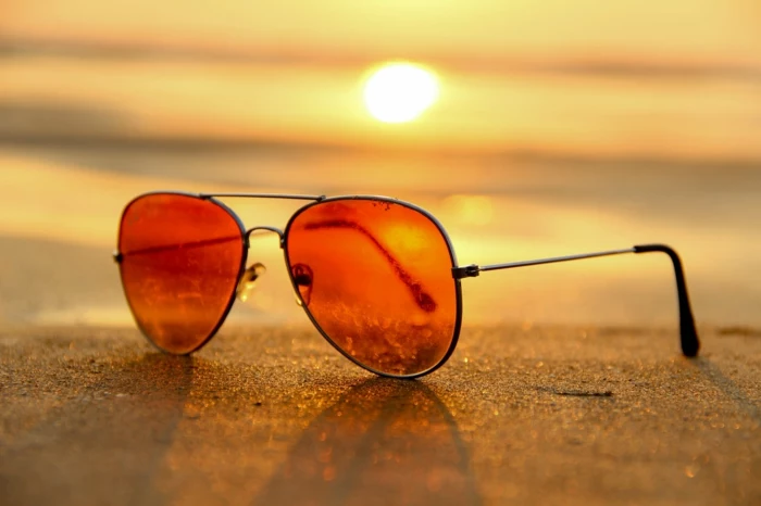 Ray Ban Sonnenbrille mit roten Gläsern, beim Sonnenuntergang auf einem Strand