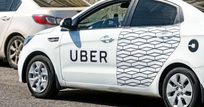 ein weißes Auto mit der Aufschrift Uber mit gemusterte Tür, ein Logo von Uber darauf