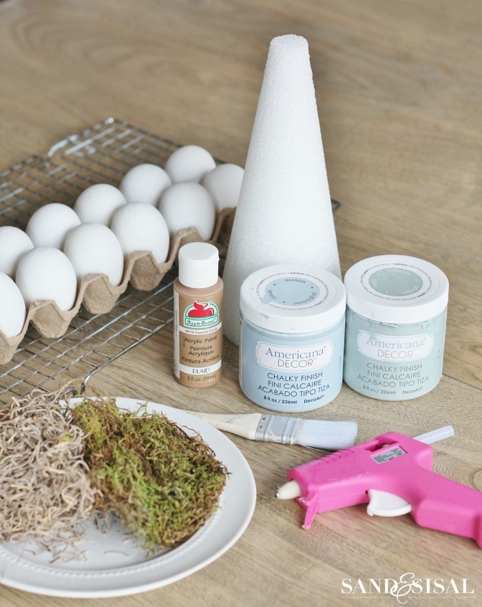 Materialien für cooles DIY Projekt für Ostern, Kegel aus Styropor, Acrylfarben und Pinsel, Heißkleber und Moos, weiße Eier 