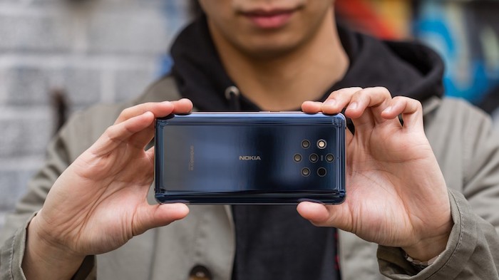 kleines dunkelblaues smartphone nokia 9 pureview mit fünf kleinen zeiss-kameras, ein junger mann, zwei hände