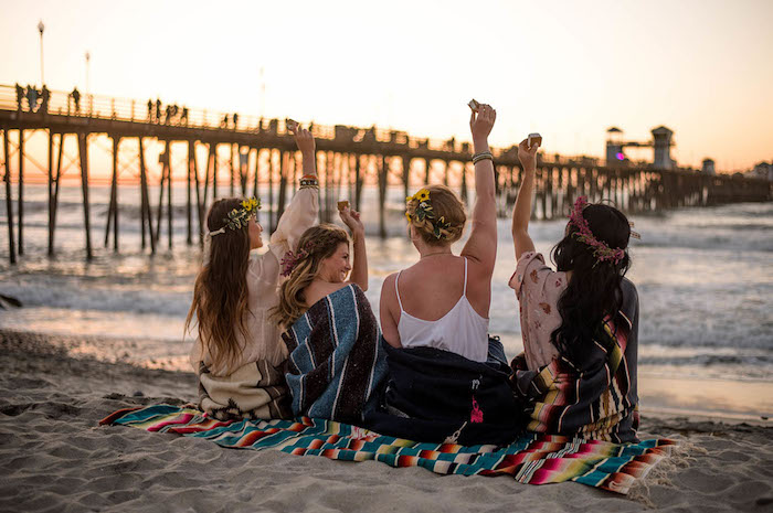 Junggesellinnenabschied auf dem Strand, Sonnenuntergang zusammen mit besten Freundinnen beobachten 