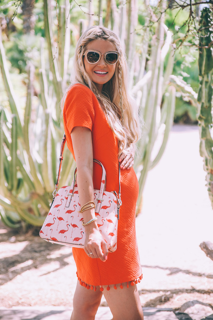 Kurzes Umstandskleid in Orange mit kurzen Ärmeln, weiße Handtasche mit Flamingo Print 