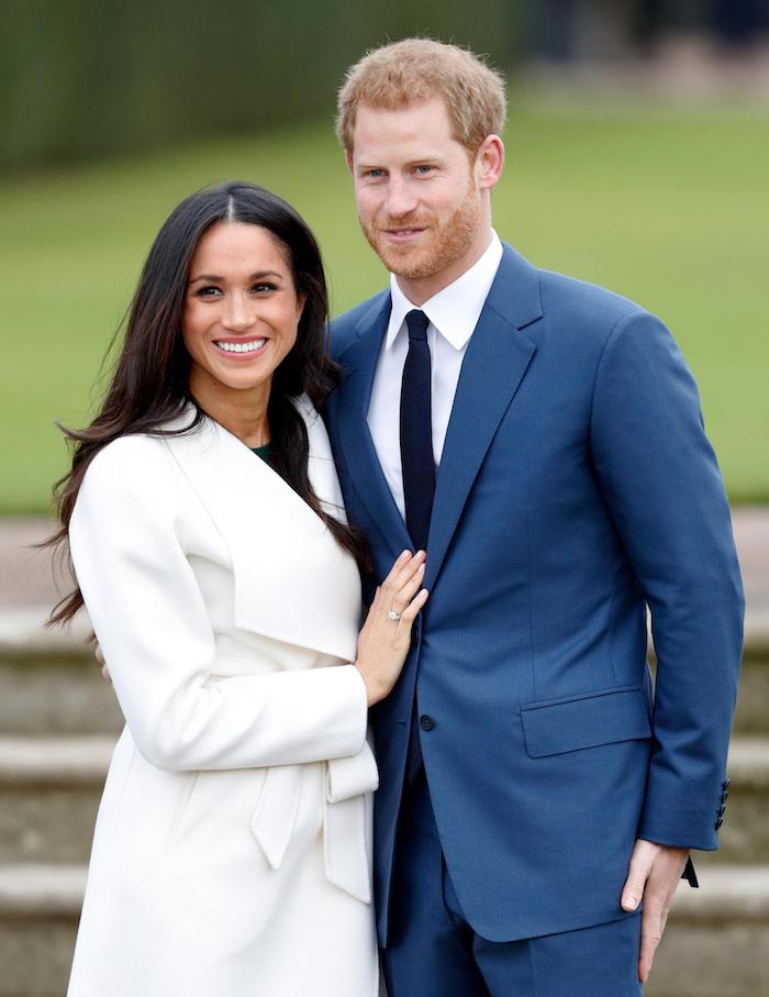 Das glückliche Paar Ehepaar Meghan Markle und Harry, Meghan mit weißem Mantel und offenen gewellten Haaren, Harry im blauem Anzug 