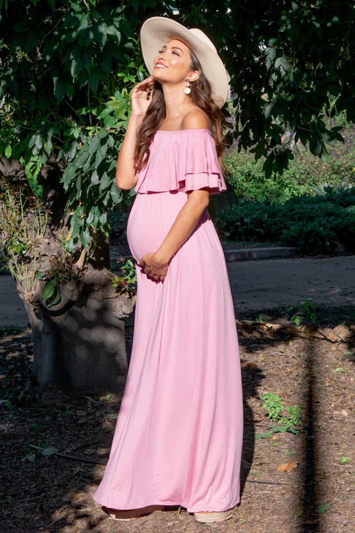 Langes Sommerkleid in Zartrosa für Schwangere und Sommerhut, braune gewellte Haare 