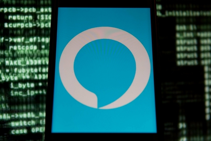 Alexa App auf Smartphone über einem Bildschirm von Windows, viele kleine grüne Buchstaben auf Hintergrund