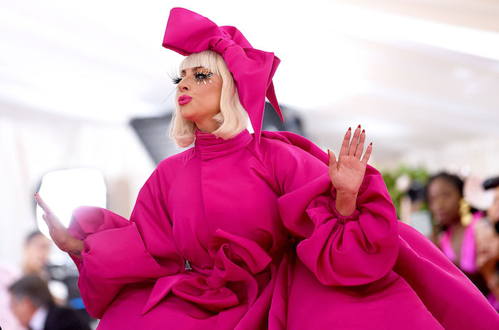 die pop-sängerin lady gaga mit blondem haar und violetten lippen und einem violetten kleid, met gala 2019