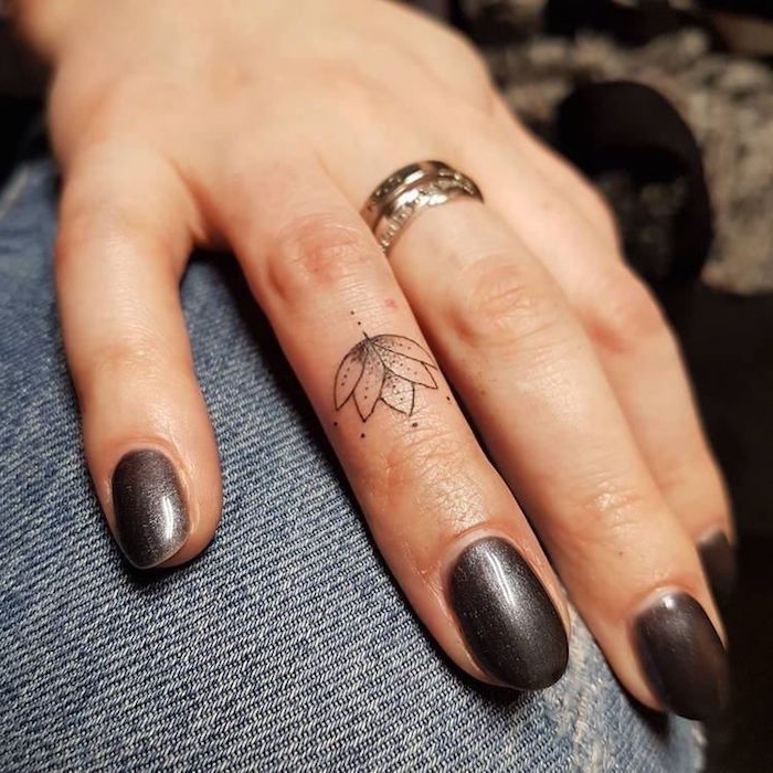 buddhistische symbole tattoo, kleine motive für frauen, lotusblüte am ringfinger, schwarzer nagellack