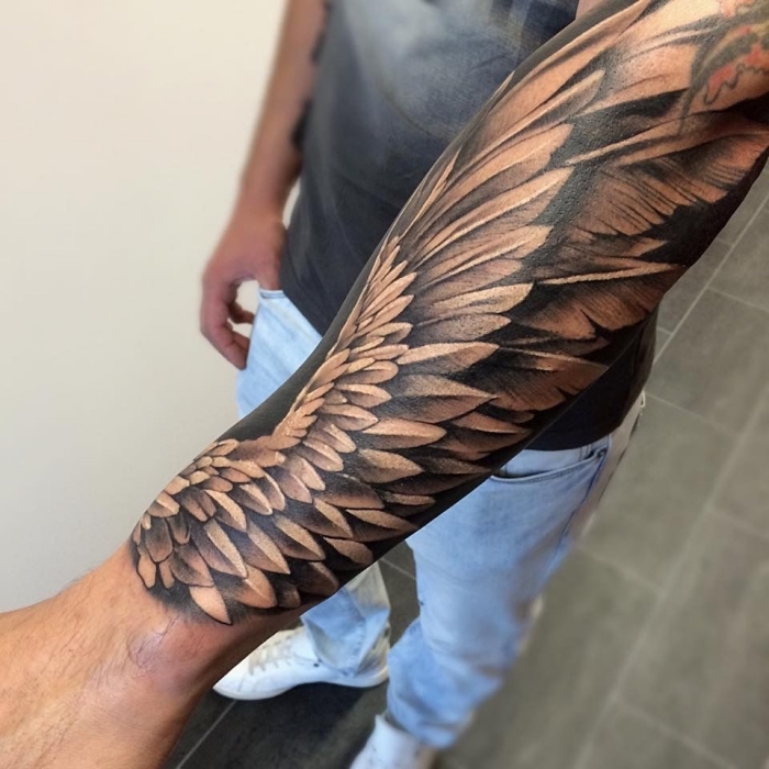 flügel tattoo designs, mann mit realitischer tätowierung am unterarm, schwarz graues tattoo am arm