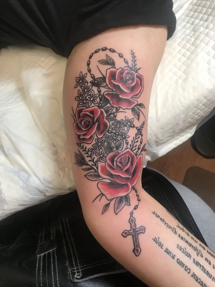 gro-es rosenkranz tattoo am oberarm, rote rosen in kombination mit kleinen schwarz grauen blumen, schriftzug