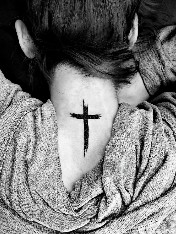 kreuz tattoo, frau mit blackwork tätowierung am nacken, kleines tattoo, realigiöses motiv, symbol