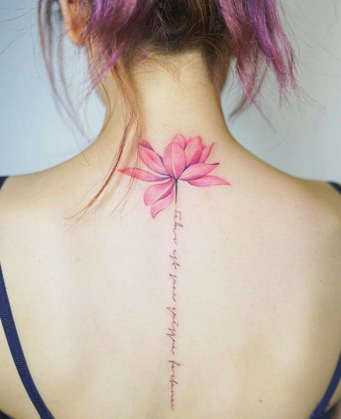rosa lotusblute mit schriftzug, lotus tattoo am rücken, frau mit wasserfarben tätowierung