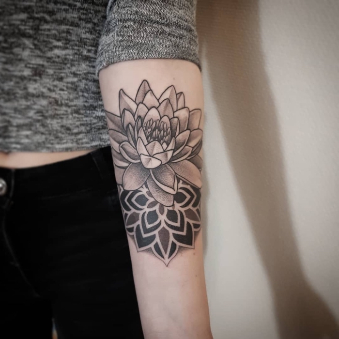 lotusblume bedeutung, schwarz graue tätowierung am arm, tattoo mit lotus als motiv am unterarm