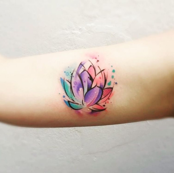 farbige tätowierung am oberarm, lotusblüte bedeutung tattoo, litus in rosa, lila und blau