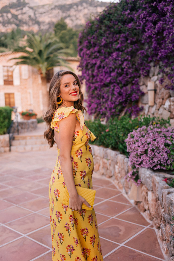 Mode für Schwangere, gelbes langes Sommerkleid mit Blumenmuster, gelbe Handtasche 
