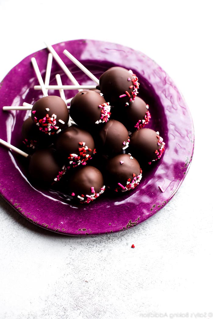 Cake Pops mit Schokolade auf lila Teller, leckeres Fingerfood zum Vorbereiten 