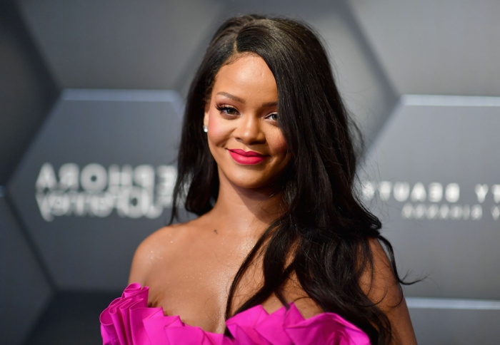 Rihanna ist mit einem rosa Kleid und passendem Lippenstift, ihre Haare sind lange und glatt