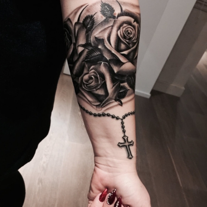 rosenkranz tattoo ideen, frau mit realitische schwarz grauer tätowierung am unterarm, drei rosen