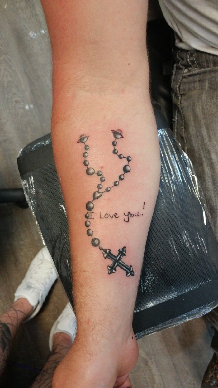 rosenkranz tattoo, realitische 3d tätowierung in schwarz und grau am arm, symbol für glauben