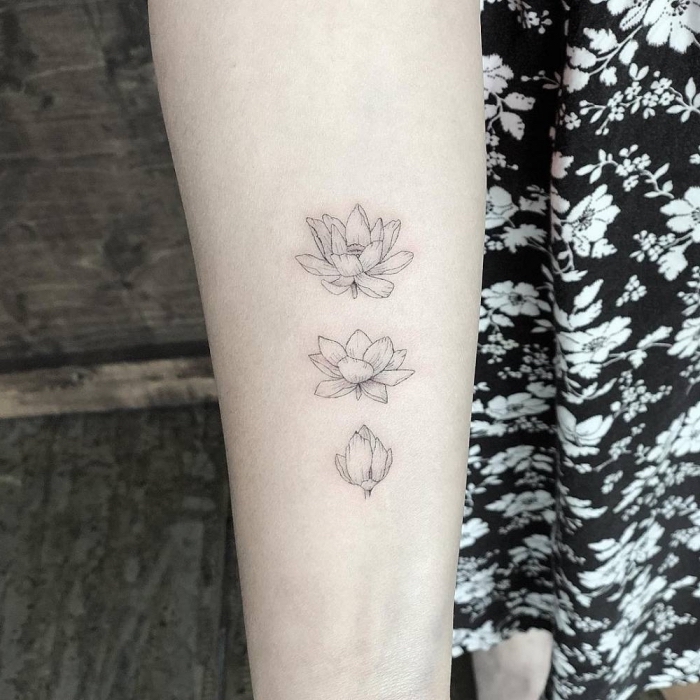 symbol für neuanfang, drei blumen am oberarm, kleine tattoo motive für frauen, tätowierung