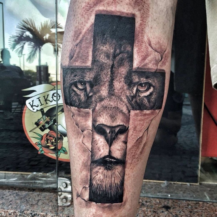 tattoo bedeutung, symbol für stärke, läwenkopf als motiv, löwe im kreuz, schwarz graue tätowierung am bein