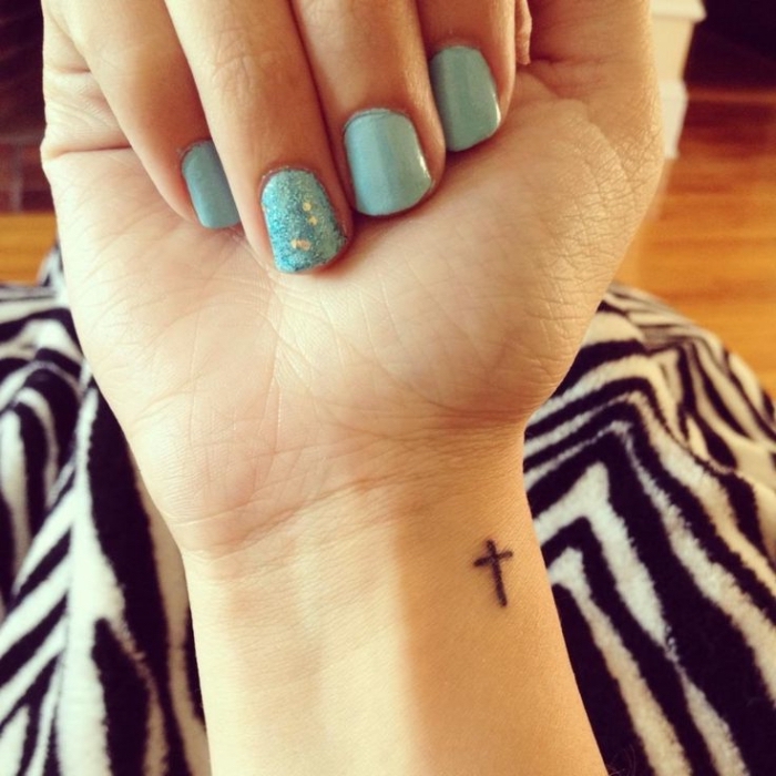 tattoo ideen klein, hellblauer nagellack mit glitzer, kleines kreuz am handgelenk, kurze nägel, sommer maniküre