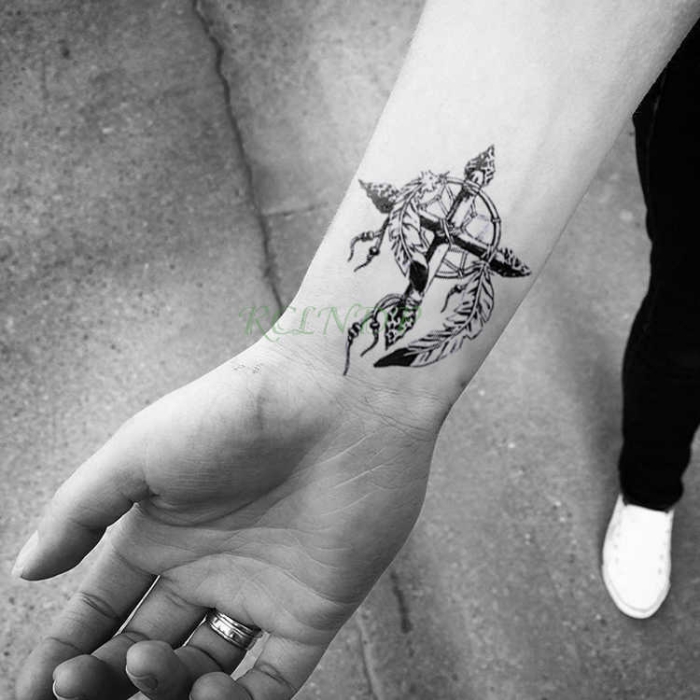 schwarz graue tätowierung am unterarm, kreuz in kombination mit traumfänger, tattoo ideen klein