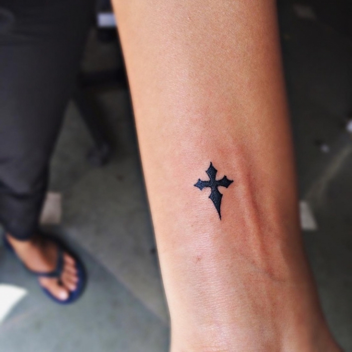 simples motiv, schwarzes kreuz am arm, tattoo ideen klein, symbol für glauben, religiöse tätowierung