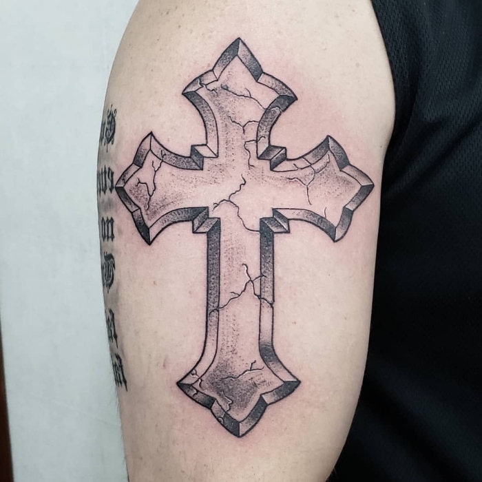mann mit großer schwarz grauen tätowierung am oberarm, tattoo kreuz, symbol für glauben