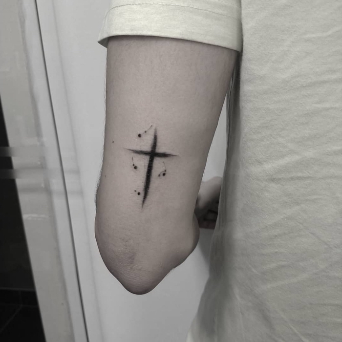 simple blackwork tätowierung über dem ellenbeogen, tattoo motive klein, schwarzes kreuz am oberarm