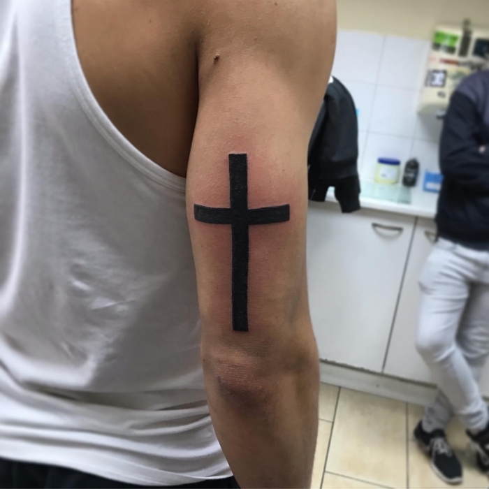 tattoo symbole für männer, schwarzes kreuz am oberarm, blackwork tätowierung über dem ellenbogen