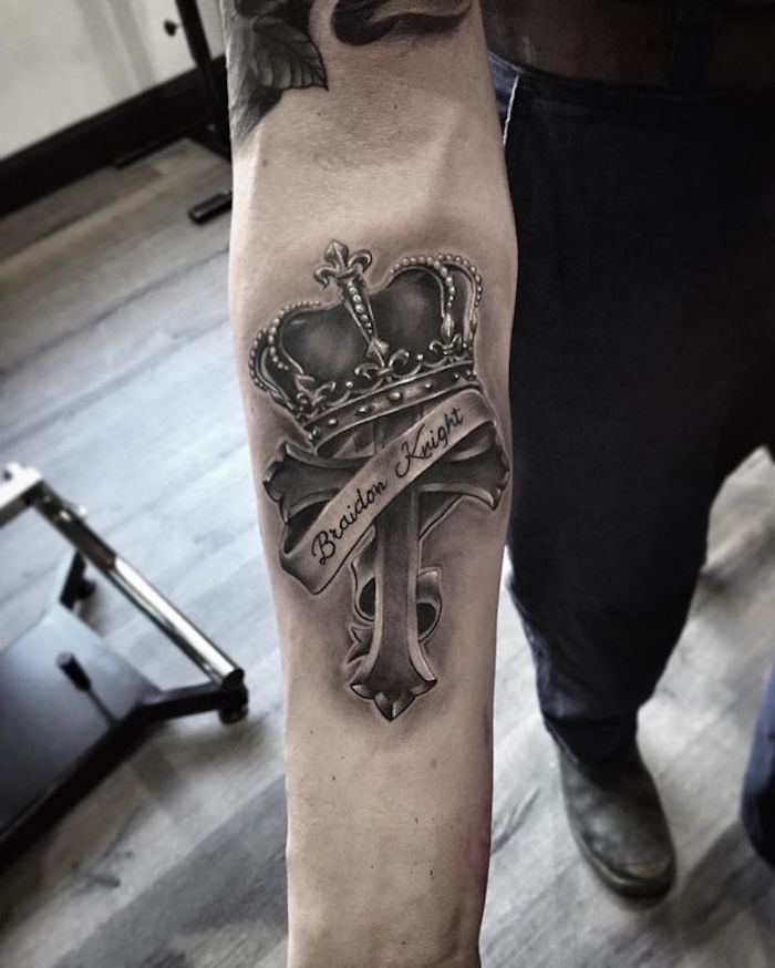 tattoo symbole ideen, realitische 3d tätowierung am arm, kreuz mit krone und schleife, schriftzug