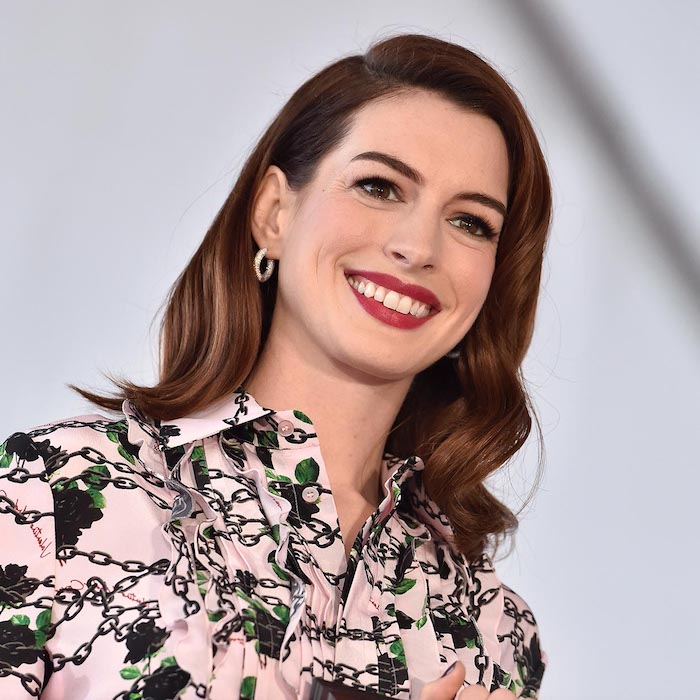 Anne Hathaway mit offenen gewellten Haaren, rotem Lippenstift, schwarzer Mascara 