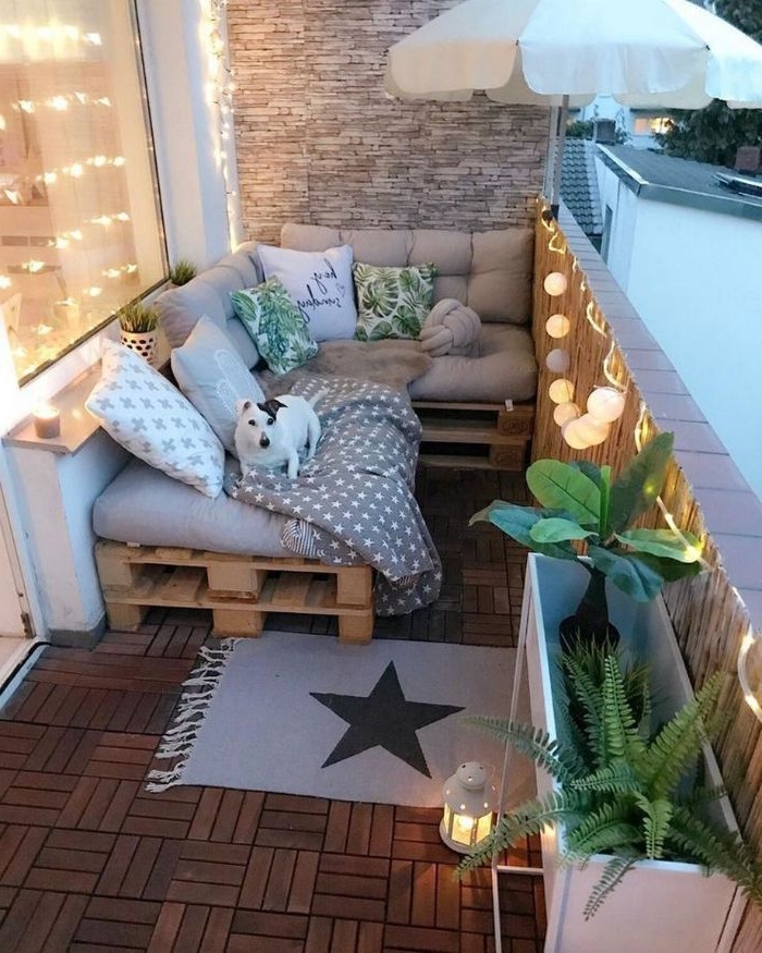 balkon ideen, dekor lampen, teppiche, paletten sofa mit kissen, ein hund liegt auf dem sofa