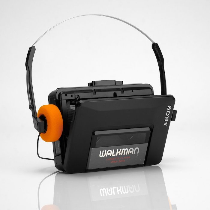 ein schwarzer kleiner walkman von sony mit orangen kopfhörern, gerät zum musik hören