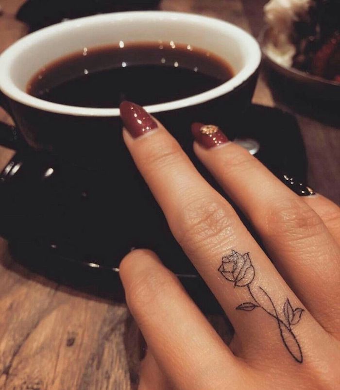 Rosen Tattoo am Mittelfinger, schöne Blumen Tattoos für die Hand, dunkelroter Nagellack mit Kristallen, Tasse Kaffee 