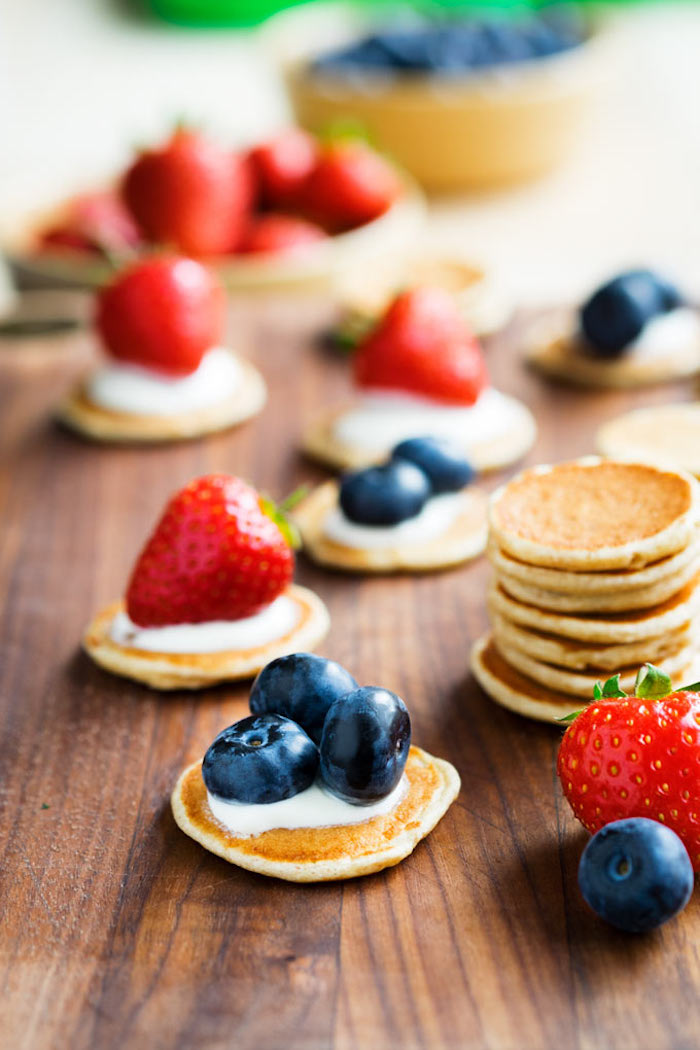 Mini Pfannkuchen mit Vanillecreme, frischen Blaubeeren und Erdbeeren, kleine Häppchen für Party 