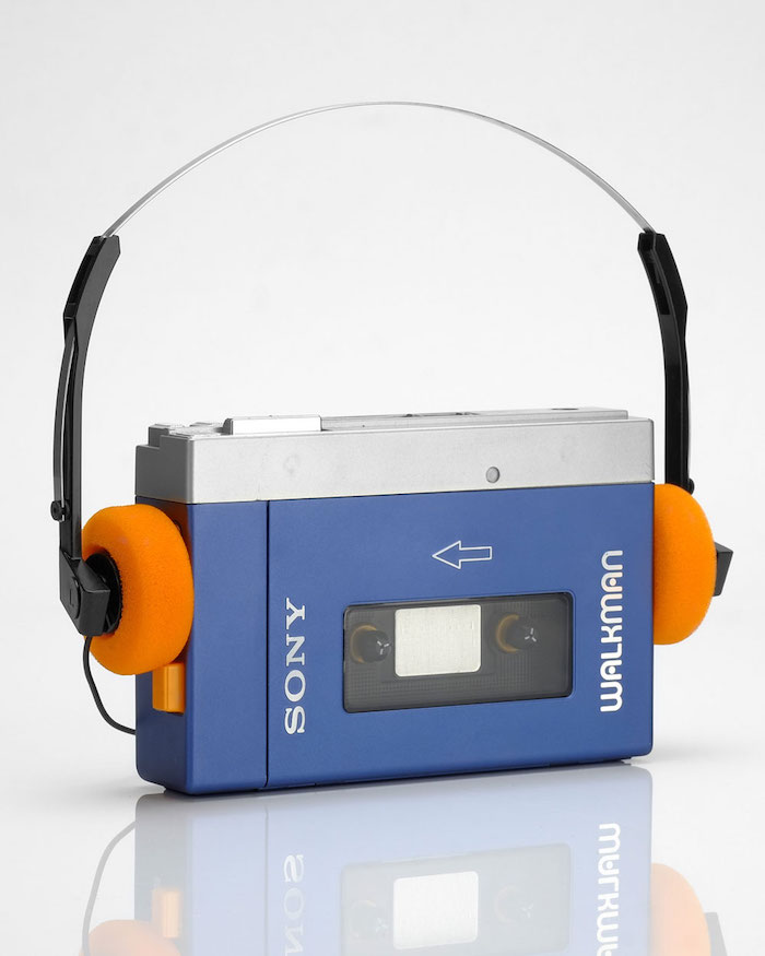 ein kleiner blauer walkman von sony mit kassette und kleinen orangen kopfhörern
