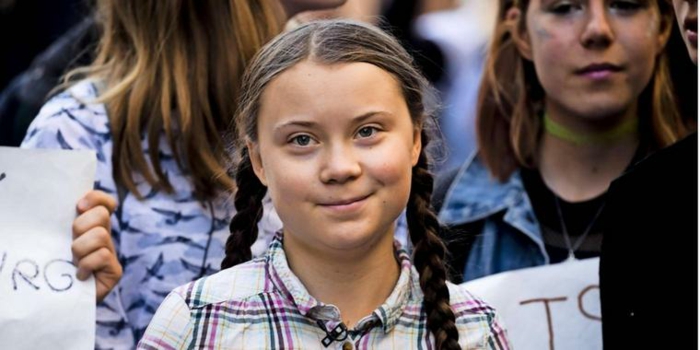 Greta Thunberg, hat zwei Zöpfe und ein kariertes Hemd bei einer Demonstration 