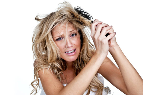 haartrends 2019, gesundes blondes haar pflegen, lochen in den haaren, eine frau versucht ihre haare zu kämmen