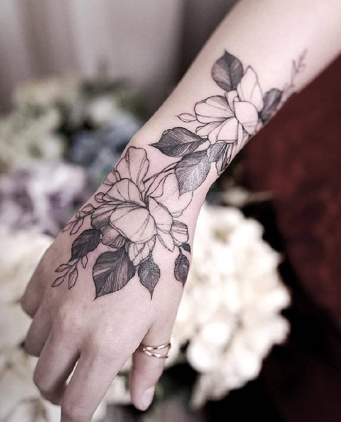 Blumen Tattoo an der Hand, zwei Ringe am Daumen, weibliche Tattoo Motive mit Bedeutung 