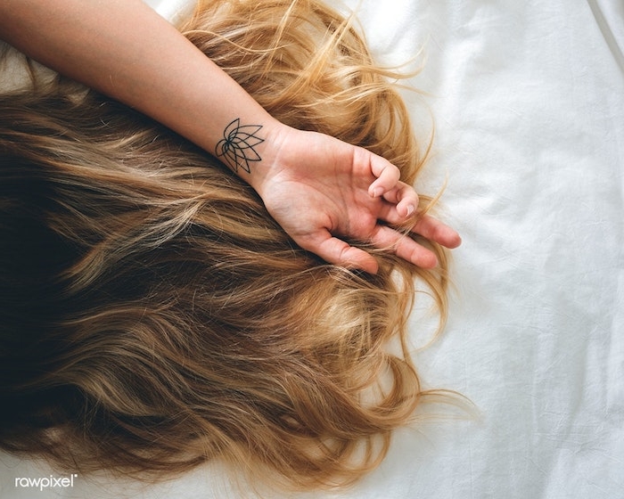 Lotus Tattoo am Handgelenk, Ideen für Blumen Tattoos, lange dunkelblonde Haare 