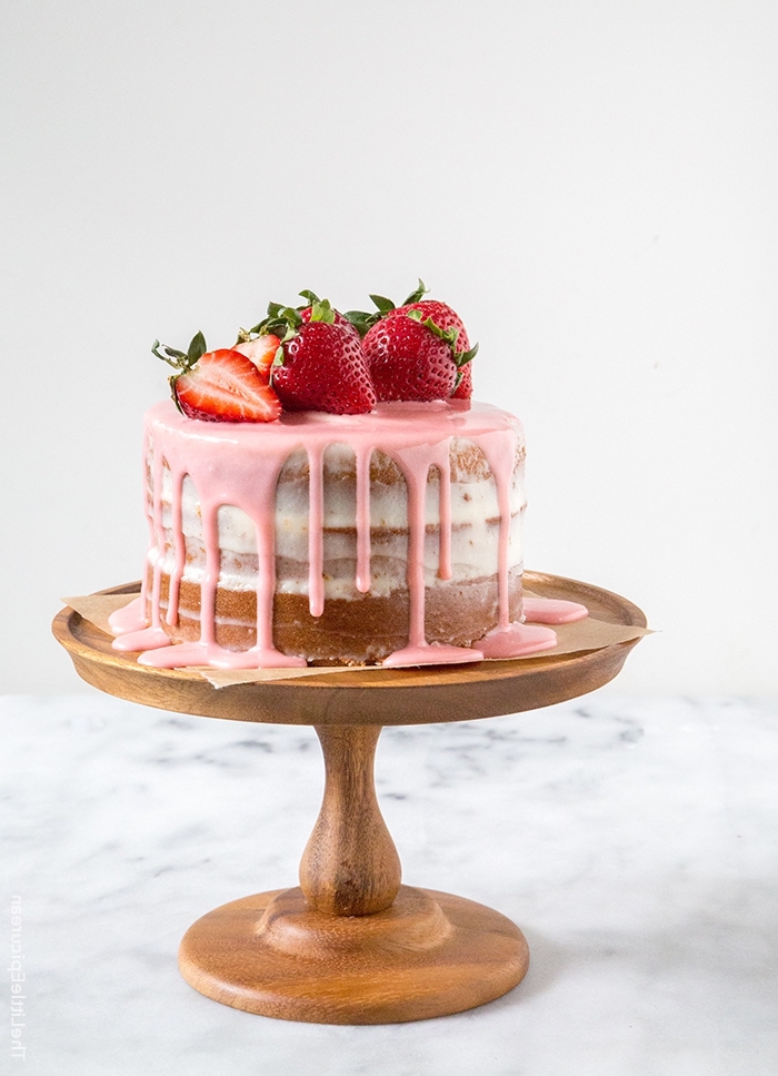 cake mit füllung aus muttercreme dekoriert mit rosa glasur und erdbeeren, erdbeer torte