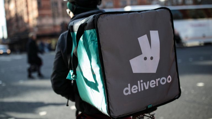 ein Fahrer mit dem Logo von Deliveroo mit weißem Buchstaben, grüne Tragetasche