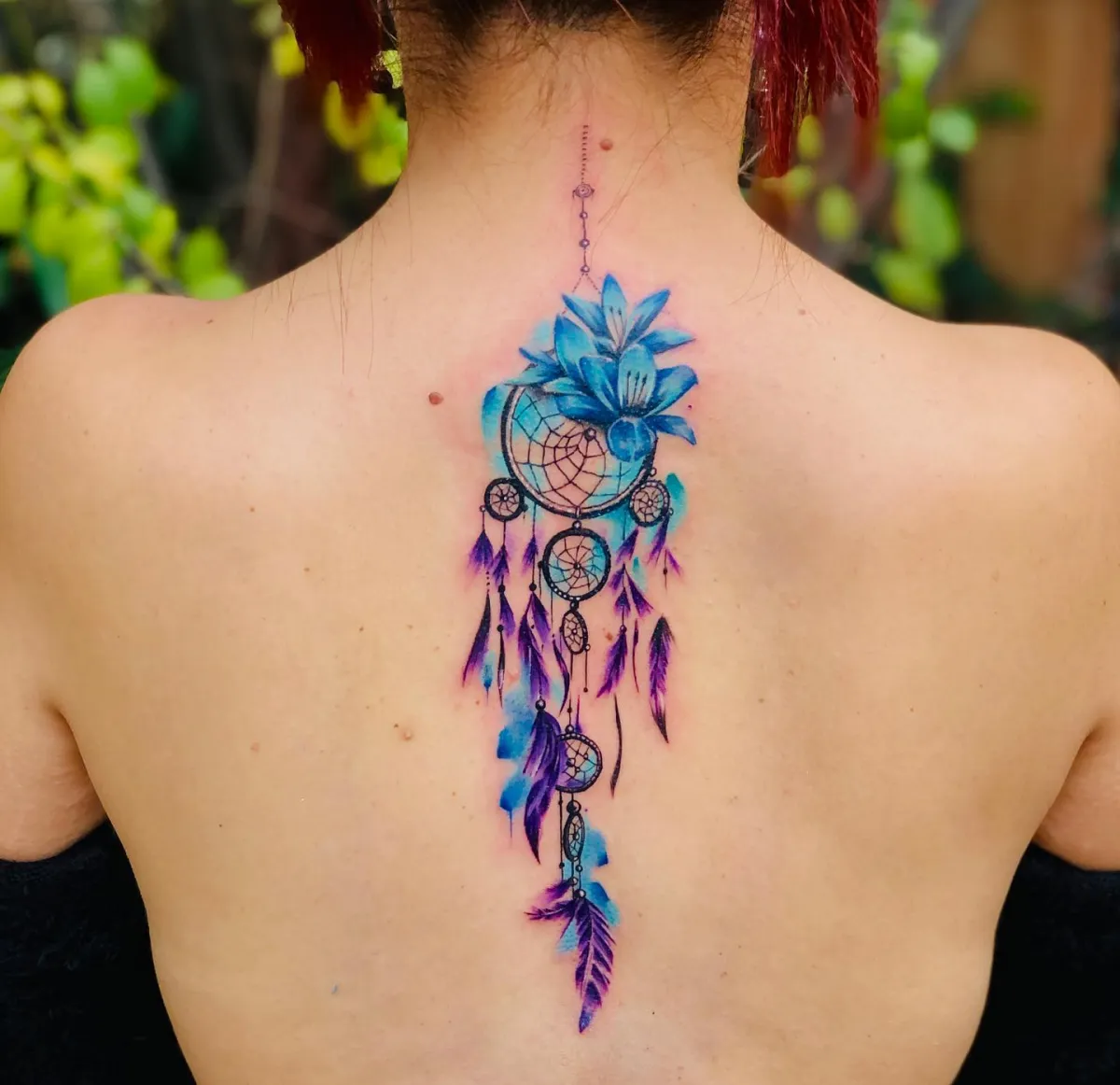 farbiges traumfänger tattoo am rücken blaue und lila federn