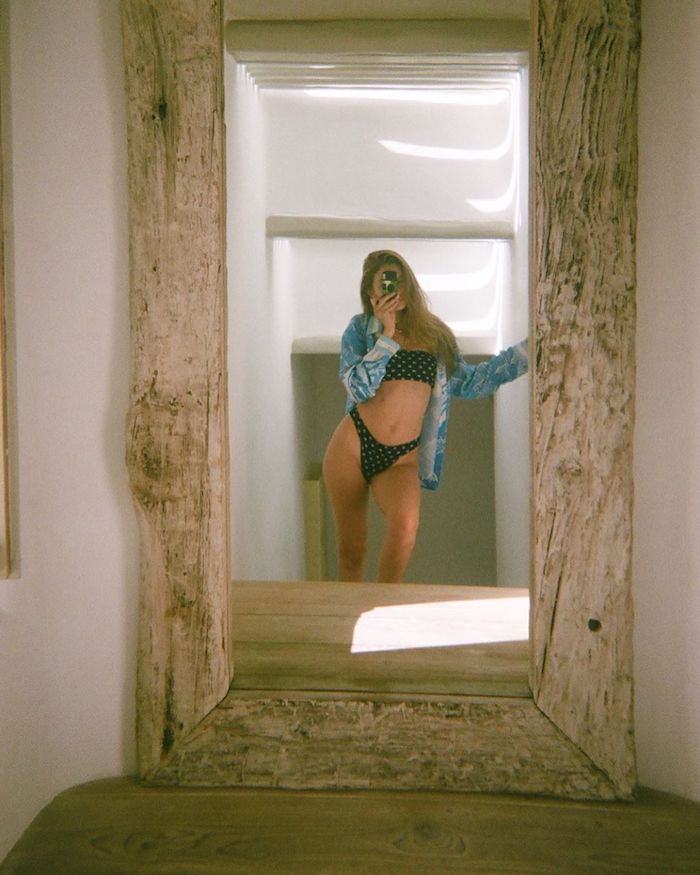 Das Supermodel Gigi Hadid auf der griechischen Insel Mykonos, schwarze Bikini und blaues Hemd, Spiegel mit Holzrahmen