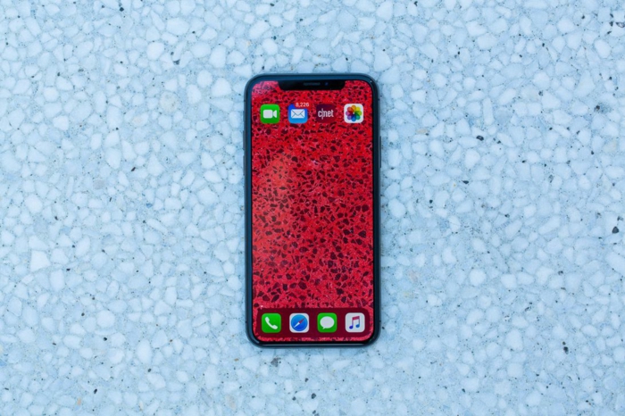 iPhone 11, ein rotes Smartphone in dem Badezimmer, es fotografiert die Fliesen