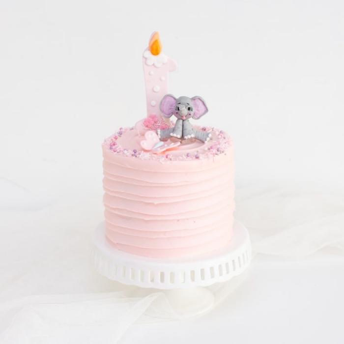 kuchen zum 1 geburtstag, torte für mädchen, geburtstagstorte dekoriert mit rosa creme und kleiner figur, elefant
