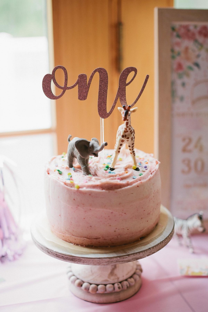 torte dekoriert mit rosa kreme und zwei figuren, kuchen zum 1 geburtstag, giraffe, elefant